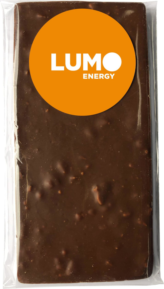 A chocolate bar wrapped in clear packaging, coated in milk chocolate, with a circular sticker on the front.