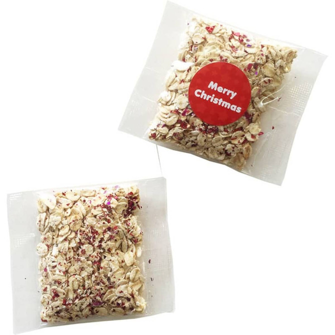 A clear packet containing a mixture of oats with festive decorations, featuring a red circular sticker.