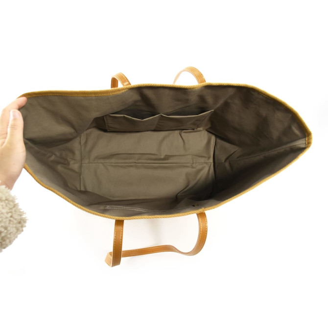 A spacious Virra Kraft paper tote bag in a mustard colour with brown handles and interior pockets.