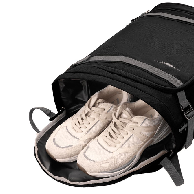 A black High Sierra travel backpack with grey accents, featuring a compartment holding a pair of white sneakers.