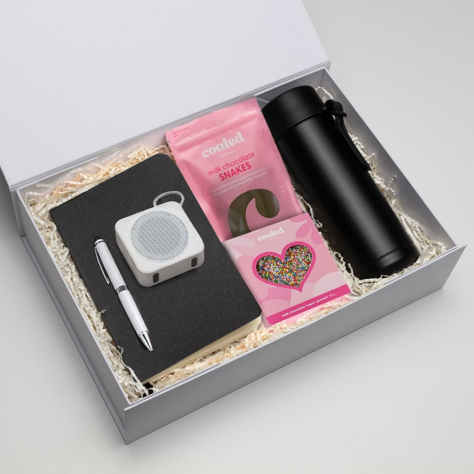 A gift box containing a black drink bottle, notebook, pen, speaker, and pink chocolate snakes.