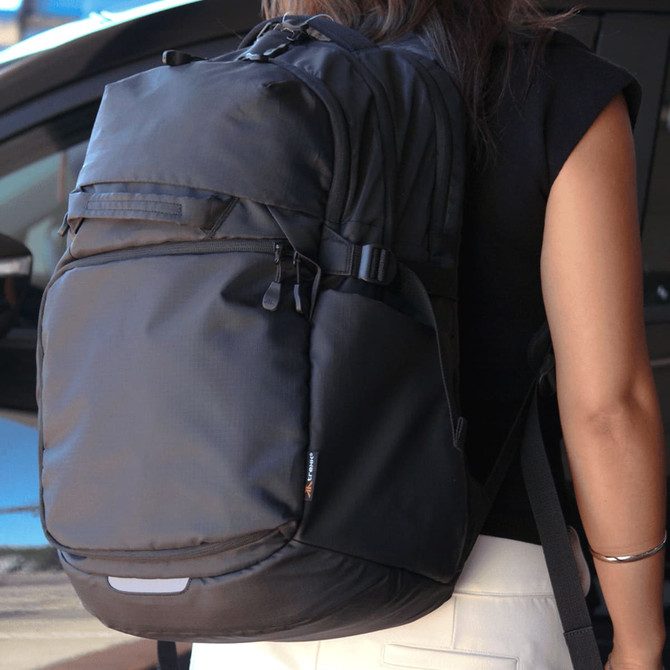 A black backpack with multiple compartments and adjustable straps, worn by a person from behind.