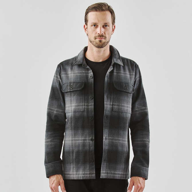 A men's shacket in black and grey Highland plaid, featuring a button front and two chest pockets.