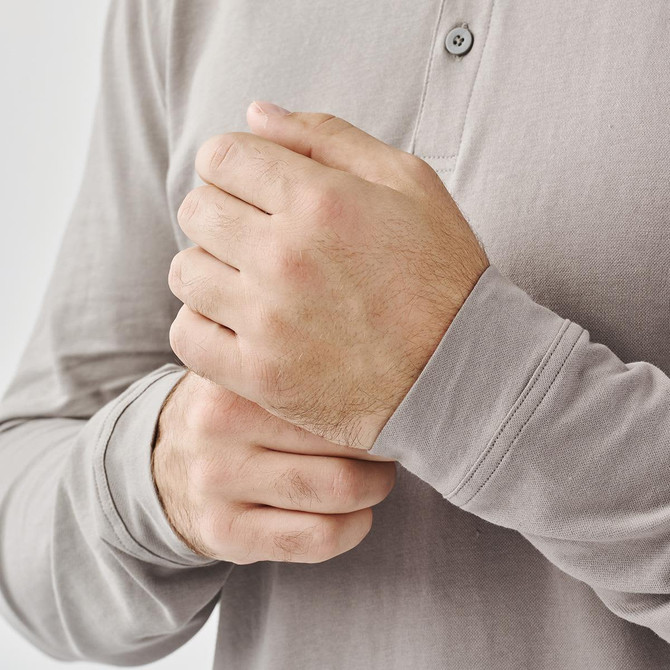 A grey long-sleeve polo shirt, featuring a collar and button placket, with hands visible on the sleeve.