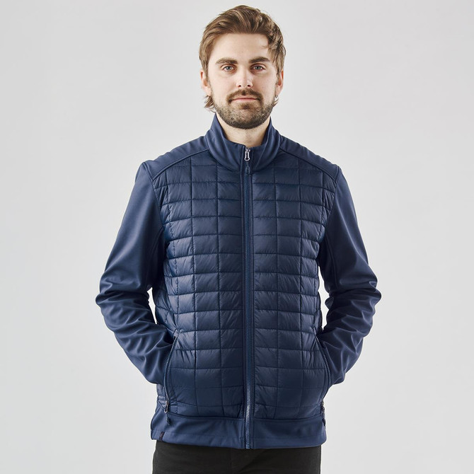 A man wearing a navy thermal softshell jacket with a quilted front, featuring a zip and side pockets.