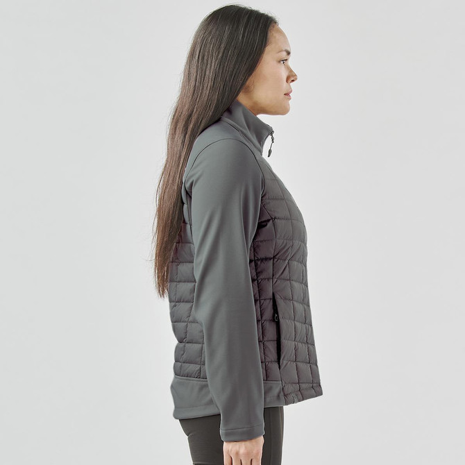A women's softshell jacket in grey, featuring a quilted design and a zip closure. The jacket includes a logo.