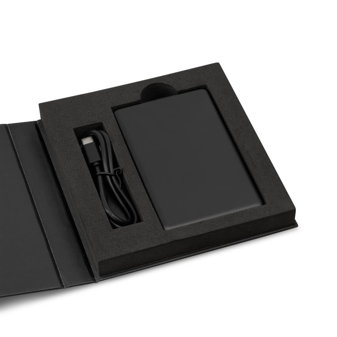 A black solid state power bank in a box with a USB cable, presented on a black foam insert.