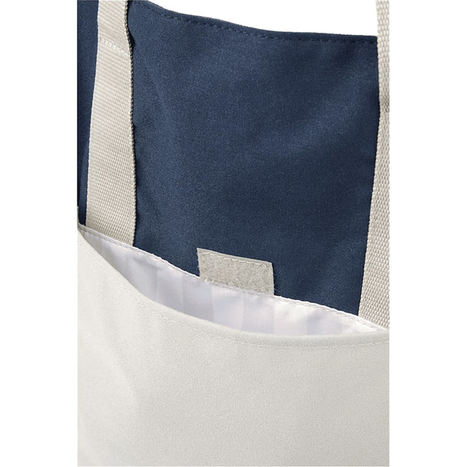 A beige tote bag with navy accents, featuring a simple design and a grey label inside the pocket.