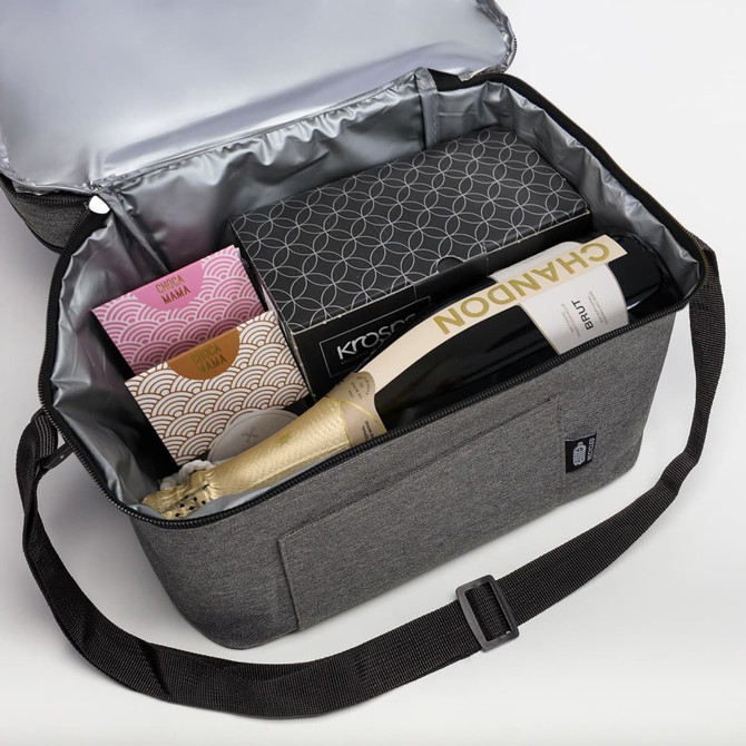 A drink bag in grey containing champagne, chocolates, and a box, with a silver insulated lining.