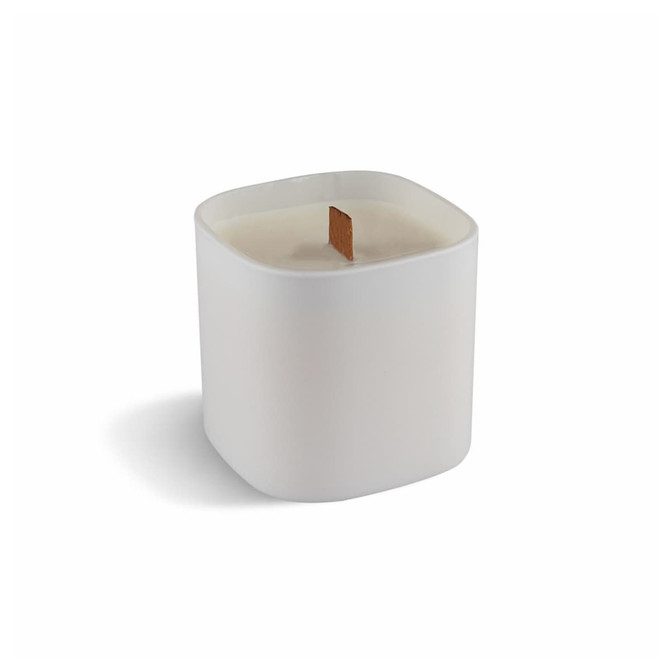 A premium square glass candle in white, featuring a wood wick. It has a smooth, minimalist design and a logo.