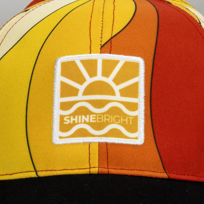 A vibrant multi-coloured cap featuring a logo with a sun and wave design.