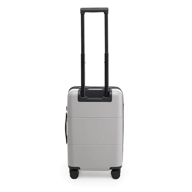 A silver carry-on suitcase with a retractable handle and wheels, featuring a simple design and a logo.