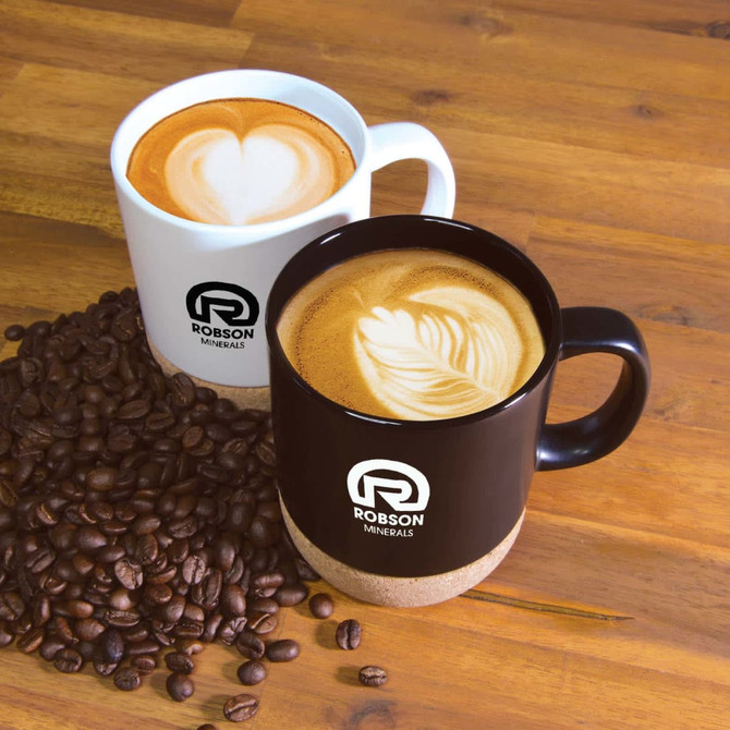 A ceramic mug with a cork base in black and white, featuring a logo, placed next to coffee beans.