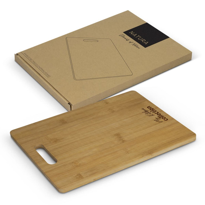 A bamboo chopping board in a rectangular shape, placed near its eco-friendly packaging. The board features a handle.