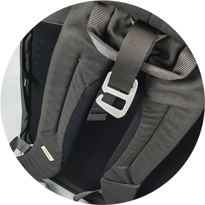 A close-up of a black Osprey Arcane Roll Top Backpack’s adjustable straps and buckle detail. The bag features branding.