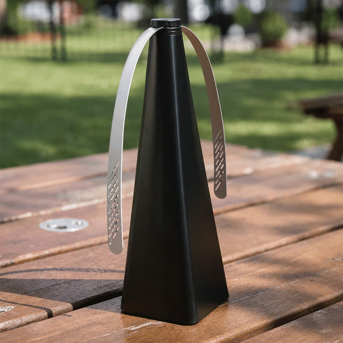 A black triangular fan with metal blades, placed on a wooden table in an outdoor setting.