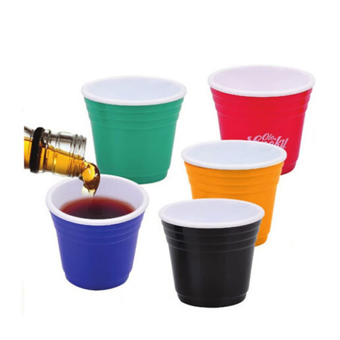 A set of five mini plastic cups in green, orange, blue, black, and red, with a pouring bottle above.