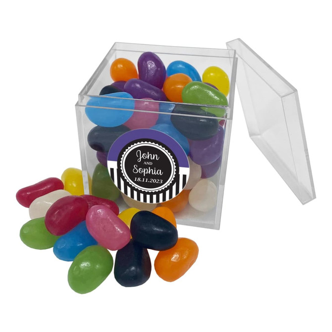 A clear cube filled with colourful jelly beans in various shades, with some scattered around it.