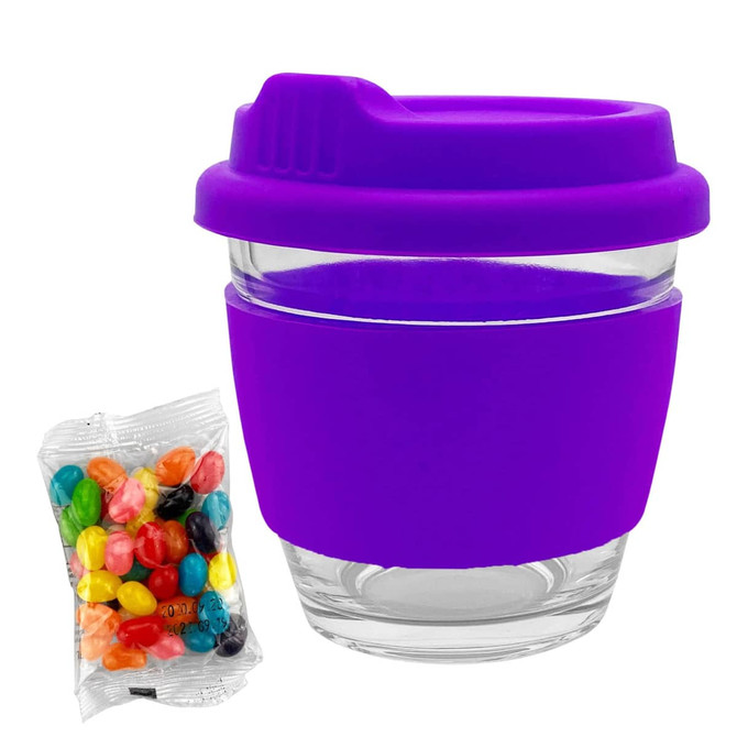 A reusable coffee cup featuring a clear glass body and a vibrant purple silicone sleeve and lid, alongside a bag of jelly beans.