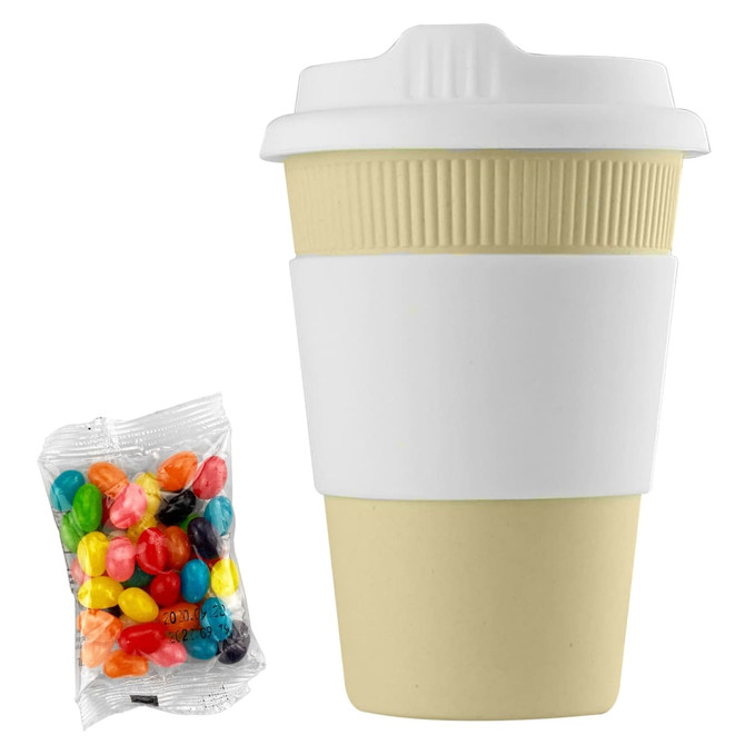 A reusable 12oz bamboo coffee cup in light beige with a white silicone sleeve, alongside a bag of colourful jelly beans.