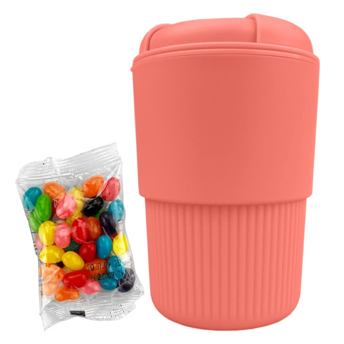 A reusable coffee cup in coral with a ribbed design, accompanied by a bag of colourful jelly beans.
