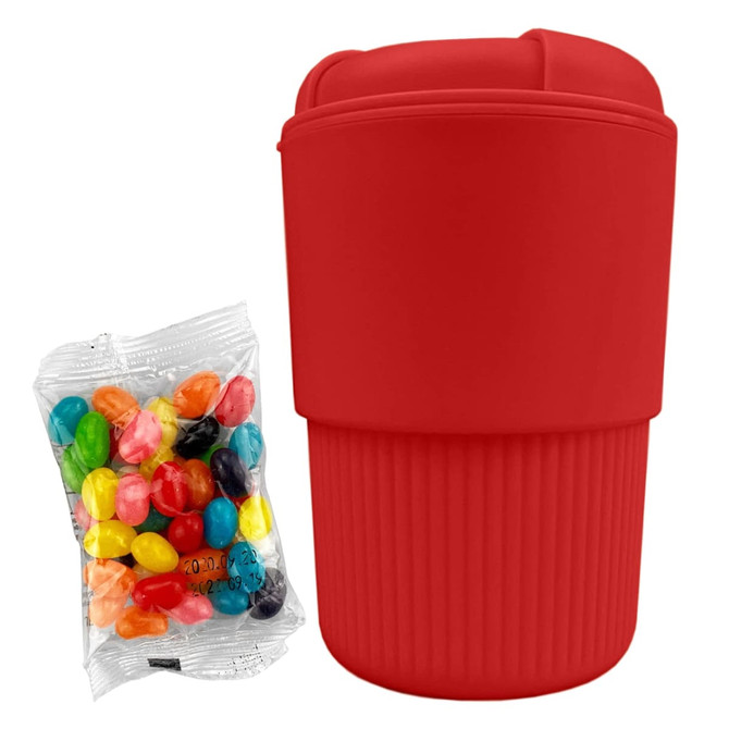 A red reusable coffee cup with a silicone sleeve and a packet of colourful jelly beans beside it.