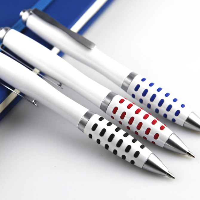 Three metal pens in white with patterned grips in red, blue, and black, resting on a notebook. Each pen features a logo.