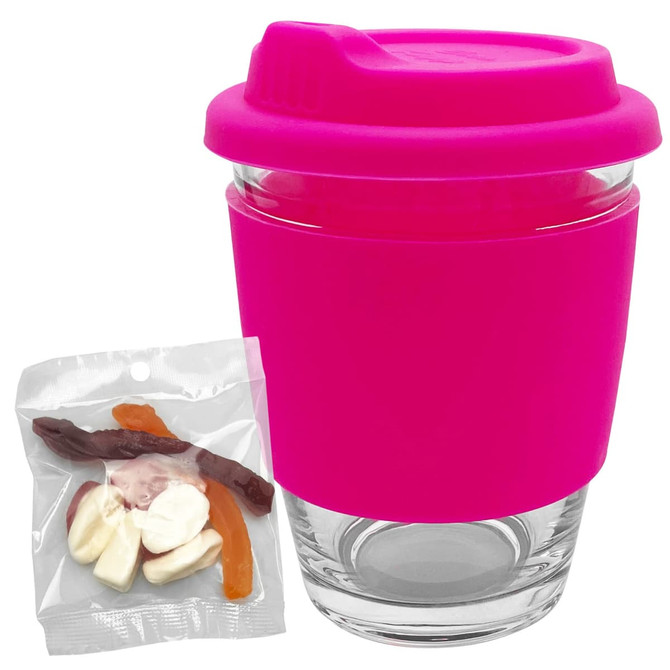 A reusable coffee cup with a bright pink silicone lid and grip, accompanied by a bag of assorted jelly candies.