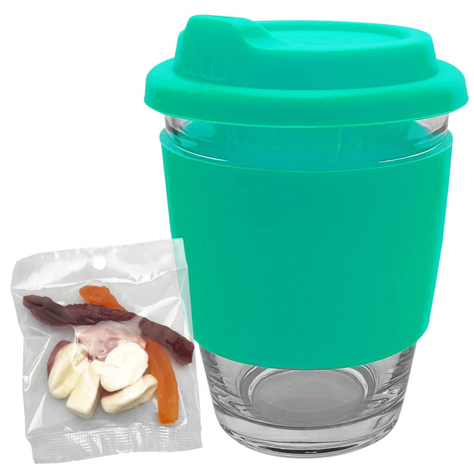 A reusable coffee cup with a turquoise silicone sleeve and a transparent glass body, accompanied by a pack of jelly candies.