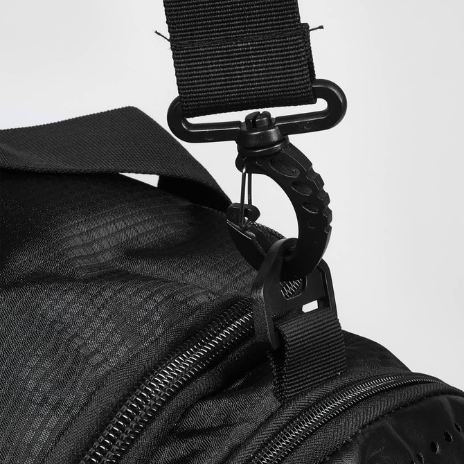 A close-up of a black duffle bag strap with a metal clip attachment. The bag has a textured surface.