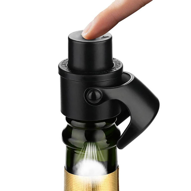 A black champagne stopper is being pressed down on a green bottle, featuring a finger on top. The product has a sleek design.