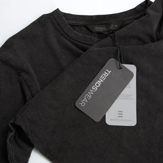 A faded black unisex T-shirt featuring a logo and a hang tag detailing care instructions.