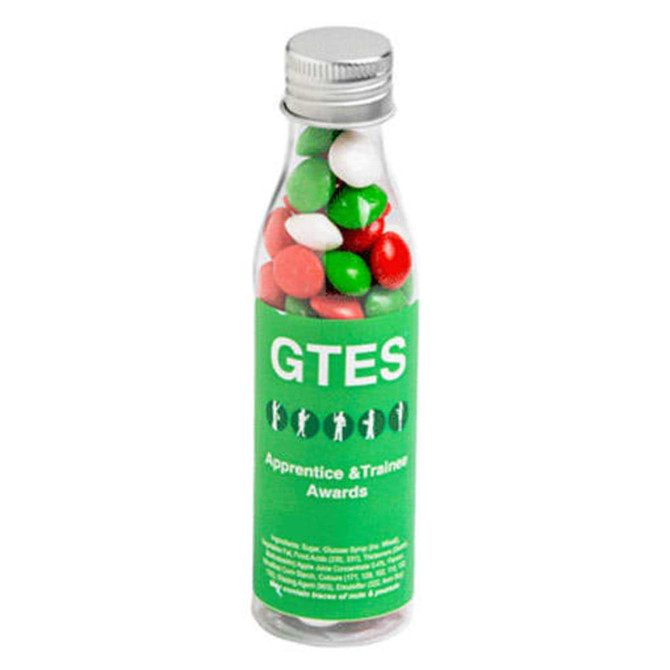 A drink bottle filled with green, red, and white chewy fruit candies. The bottle features branding on its label.