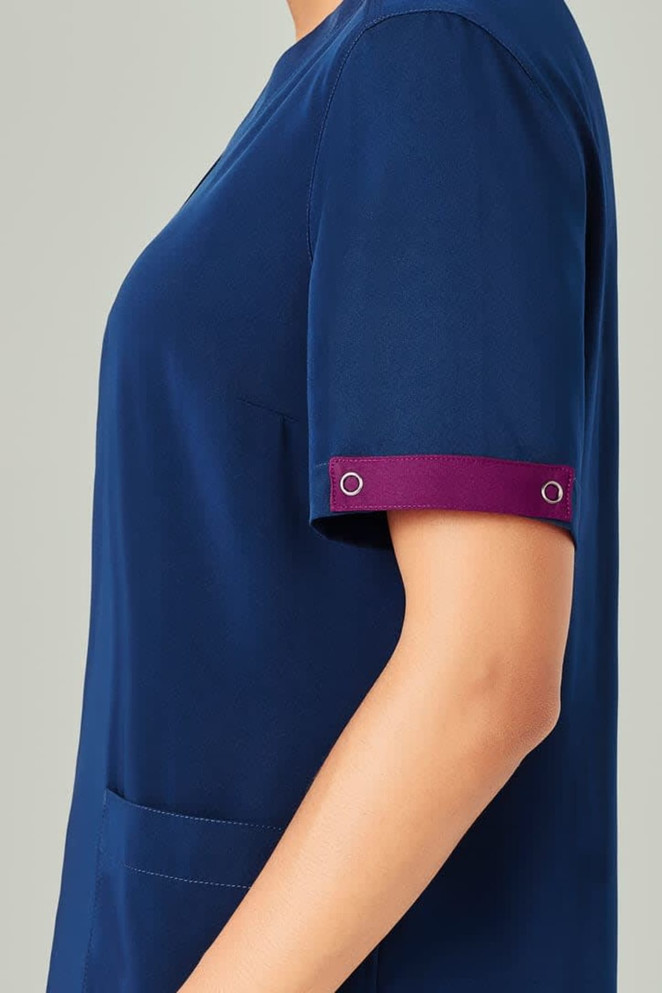 A navy blue scrub top with short sleeves featuring a maroon cuff detail and an attached logo.