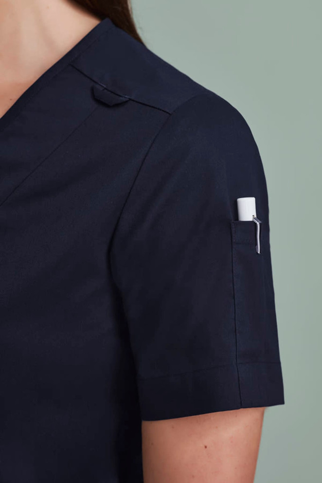 A navy women's zip front crossover scrub top featuring short sleeves and a pocket on the sleeve.