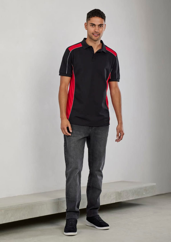 A unisex polo shirt in black with red side panels, featuring short sleeves and a logo. Styled with grey jeans.