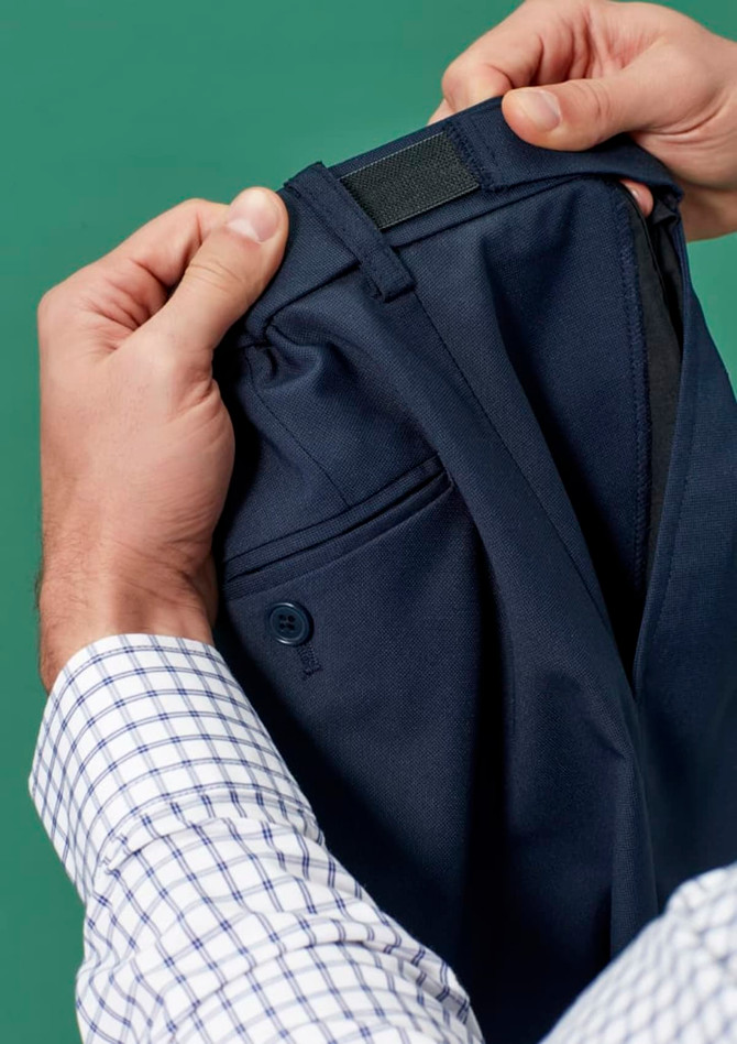 A person holding navy blue straight leg pants featuring an adjustable waist and a logo on the waistband.