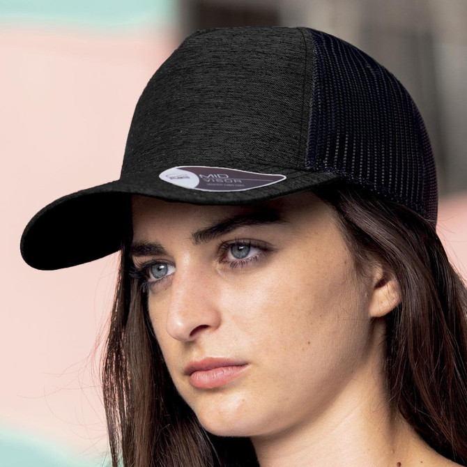 A black cap with a mesh design and a logo, worn by a model against a pastel background.