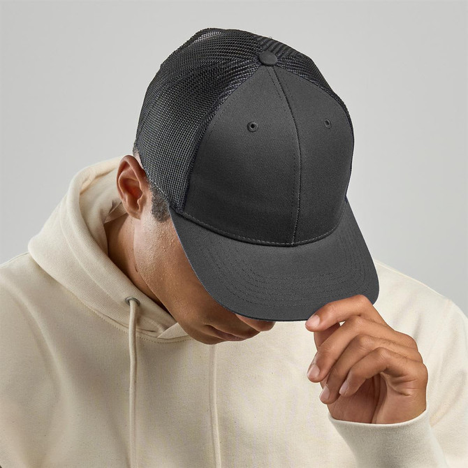 A grey trucker cap with a solid front and mesh back, worn by a person in a cream hoodie.