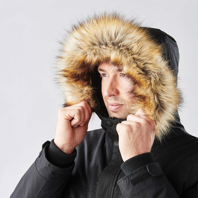 A black parka jacket featuring a fur-lined hood, worn by a man adjusting the hood around his face.