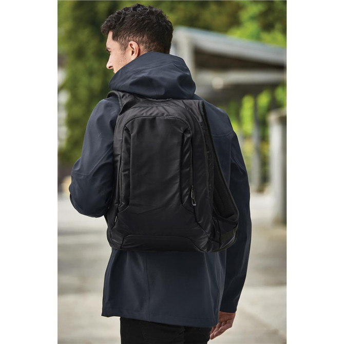 A black backpack is worn on the back of a person, featuring multiple compartments and a sleek design.