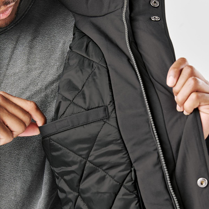 A man shows the interior pocket of a black thermal jacket, featuring a quilted lining and a hood.
