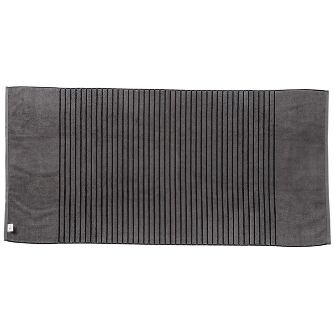 A reversible two-tone bath towel featuring a dark grey colour with striped texture and a small logo.