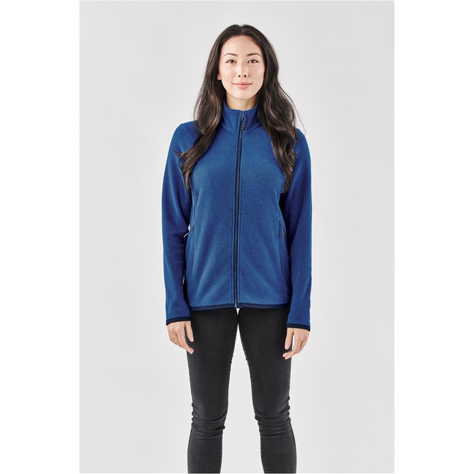 A woman wearing a full zip jacket in navy blue with a fitted design and a logo.