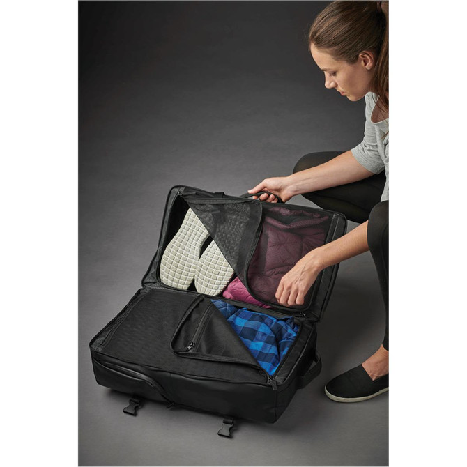 A black backpack opened to reveal neatly packed clothing items, including patterned and plain fabrics. It features a logo.