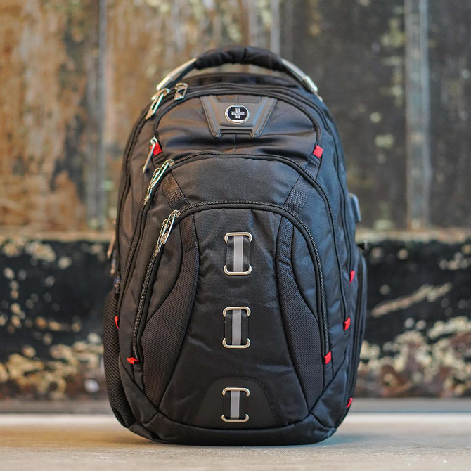 A black backpack with red accents, featuring multiple zippers and straps, and a logo on the front.