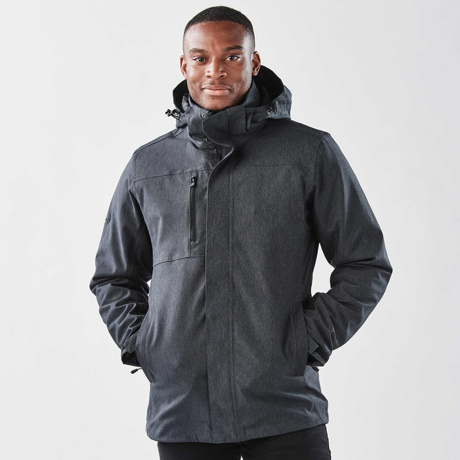 A man wearing a black jacket with a hood, featuring a zipper and pockets, against a plain background.