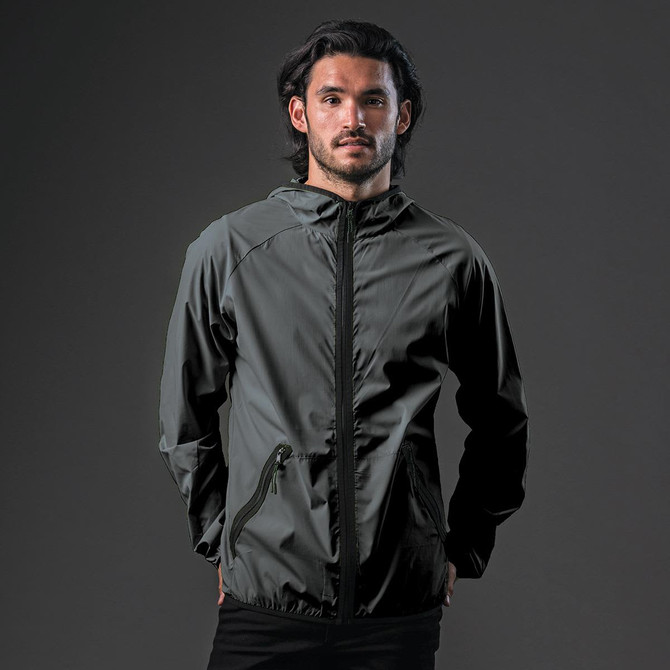 A man wearing a dark grey hooded rain jacket with a zip and a logo on the chest.