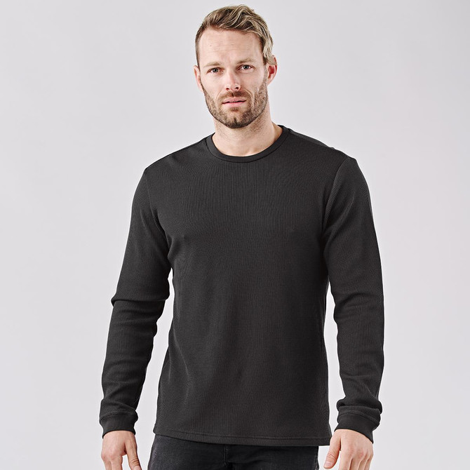 A black long-sleeve crew neck shirt on a model, featuring a simple design and a logo.