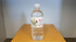 A drink bottle filled with clear water, featuring a label with graphics and a logo, on a brown surface.